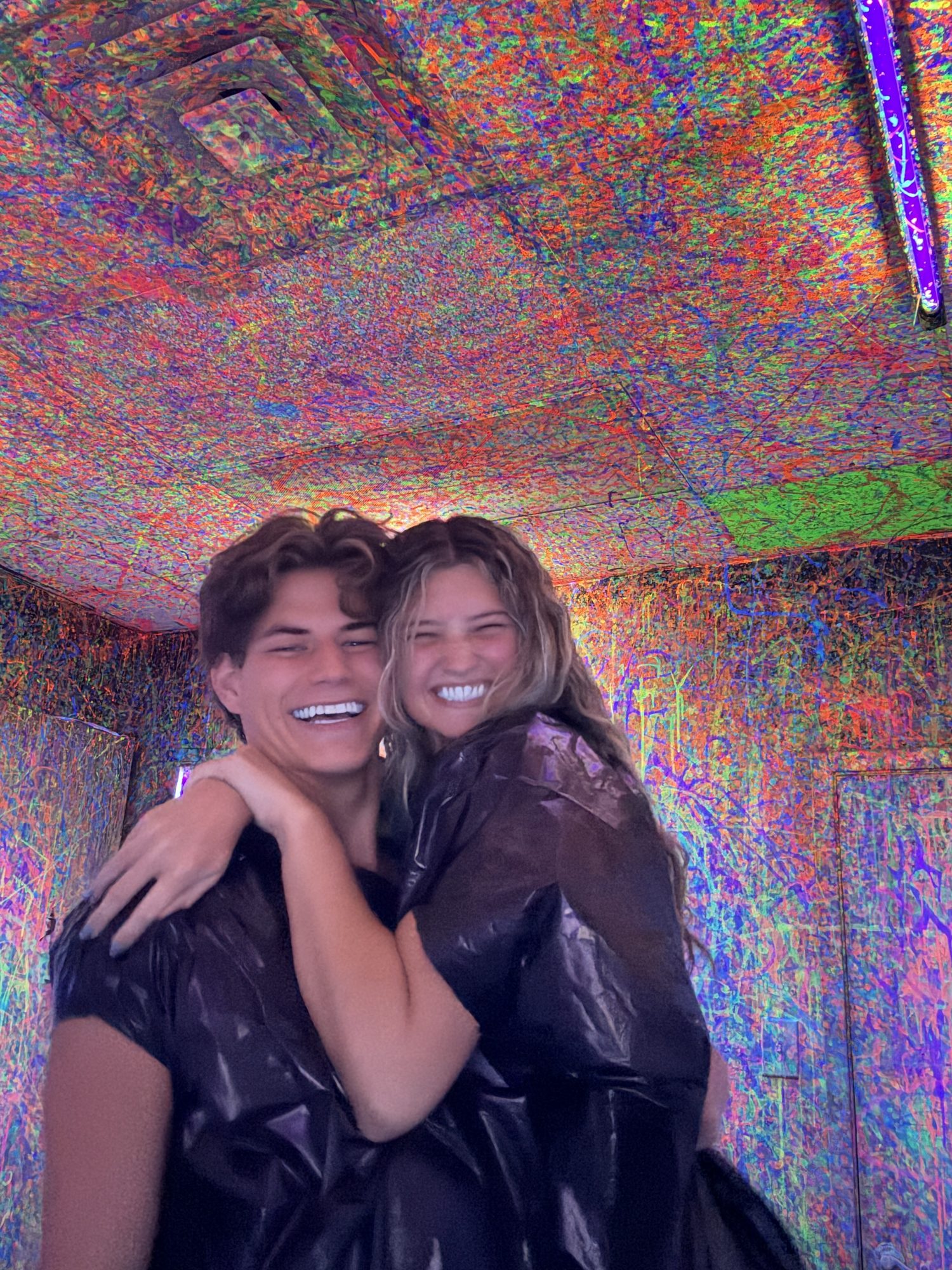 Brock and Anna laughing in a paint splatter room